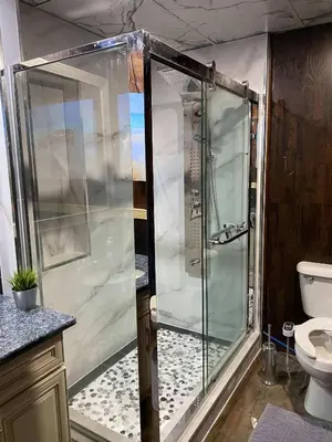 a shower with a glass door in a bathroom at Beach Front Family Cottage Ping Pong & Karaoke in Fort Erie