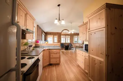 a large kitchen with wooden cabinets and wooden floors at Cottage on Crystal Beach 3BR & BBQ in Fort Erie