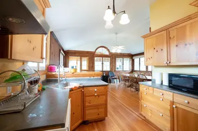 a large kitchen with wooden cabinets and a dining room at Cottage on Crystal Beach 3BR & BBQ in Fort Erie