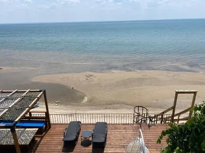 a deck with a beach with two chairs and a playground at Water Front Beach House - 3BR w BBQ & Sunset in Fort Erie
