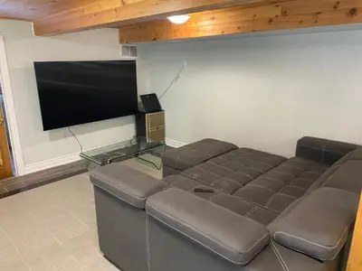 a living room with a couch and a flat screen tv at Water Front Beach House - 3BR w BBQ & Sunset in Fort Erie