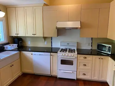 a kitchen with white appliances and wooden cabinets at Water Front Beach House - 3BR w BBQ & Sunset in Fort Erie
