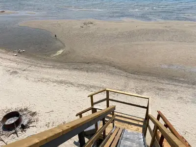 a wooden stairs leading to a beach with the ocean at Water Front Beach House - 3BR w BBQ & Sunset in Fort Erie