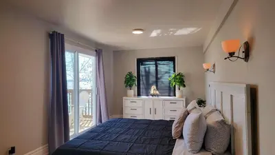 a bedroom with a blue bed and a window at Crystal Beach Waterfront Cottage - Sunset Views in Fort Erie