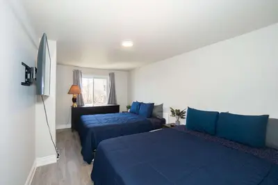 a bedroom with two blue beds and a window at Crystal Beach Waterfront Cottage - Sunset Views in Fort Erie