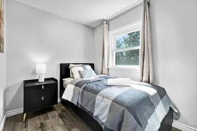 a white bedroom with a bed and a window at NEW 5 Bedroom House Near The Falls in Niagara Falls