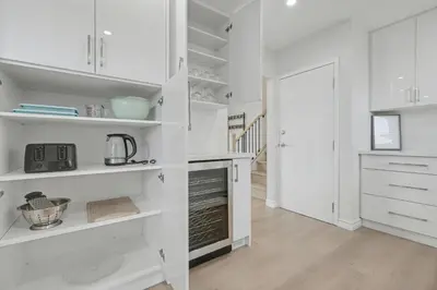 a white kitchen with white shelves and a hallway at New 3BR Home - Minutes to the Falls in Niagara Falls