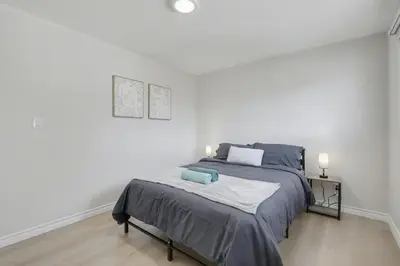 a bedroom with a large bed in a white room at New 3BR Home - Minutes to the Falls in Niagara Falls