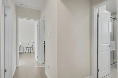 a white hallway with a door and a chair at New 3BR Home - Minutes to the Falls in Niagara Falls