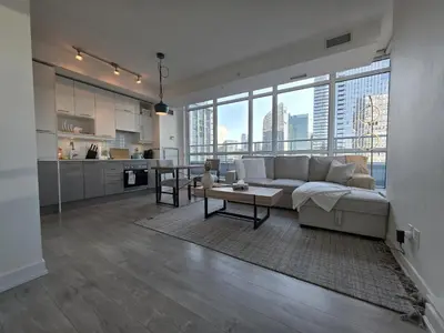 a living room with a white couch and a kitchen at Entire 1BR Luxury Downtown Toronto Condo, Free Parking, Balcony in Toronto