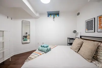 a white bedroom with a bed with a blue stuffed animal on it at Basement Suite for 2 w Private Patio in Toronto in Toronto