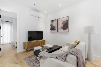 a white living room with a couch and a tv at The Brick Hotel - The Laneway in Toronto