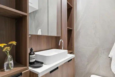 a bathroom with a white sink and wooden cabinets at The Brick Hotel - The Laneway in Toronto
