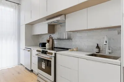 a white kitchen with white cabinets and a sink at The Brick Hotel - The Laneway in Toronto