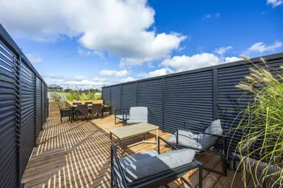 a deck with chairs and tables and a fence at The Brick Hotel - The Loft in Toronto