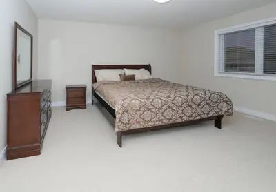 a bedroom with a bed and a dresser and a mirror at Entire home in London, Ontario, Canada in London