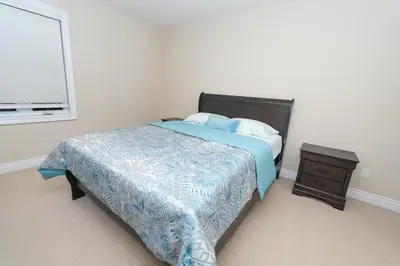 a bedroom with a bed with a blue comforter and a window at Entire home in London, Ontario, Canada in London