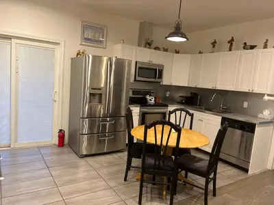 a kitchen with a table and a stainless steel refrigerator at Places to stay bbq ac heat parking wiffi in Kawartha Lakes