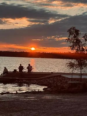three people sitting on a dock watching the sunset at Places to stay bbq ac heat parking wiffi in Kawartha Lakes