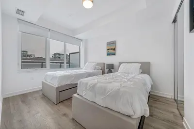 a white bedroom with two beds and a window at Your Friday Harbour Escape Awaits! in Innisfil