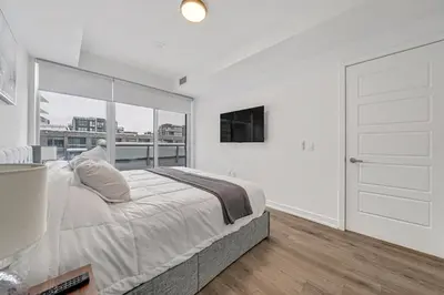 a white bedroom with a large bed and a tv at Your Friday Harbour Escape Awaits! in Innisfil