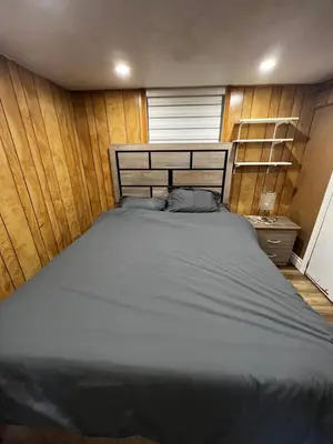 a large bed in a room with wooden walls at Prime Location 3Bedrooms, 2 Bath, Basement Apartment with parking- Streetsville Area, Close to Transit- Sleeps 6 in Mississauga
