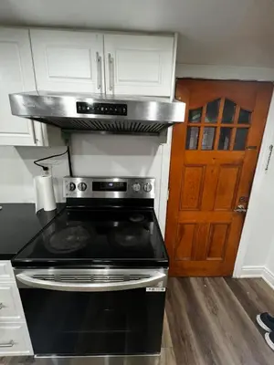 a kitchen with a stove top oven in front of a door at Prime Location 3Bedrooms, 2 Bath, Basement Apartment with parking- Streetsville Area, Close to Transit- Sleeps 6 in Mississauga