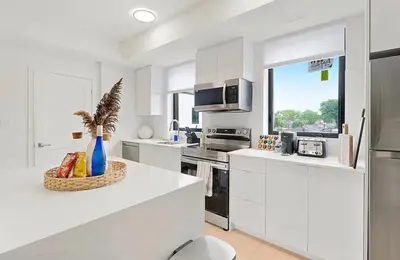a white kitchen with a bowl of fruit on a counter at 2Bdrm Penthouse Close To Falls With Parking in Niagara Falls