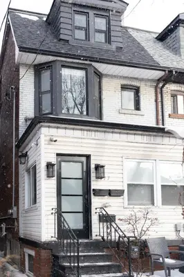 a white house with a black door and stairs at Central Getaway University of Toronto TTC Queen M in Toronto
