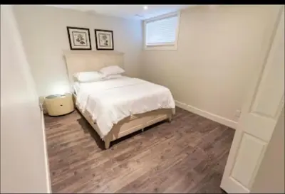 a bedroom with a white bed and a wooden floor at Modern Cozy Executive Suite with Private Entrance in London