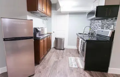 a kitchen with a stainless steel refrigerator and wooden cabinets at Modern Cozy Executive Suite with Private Entrance in London