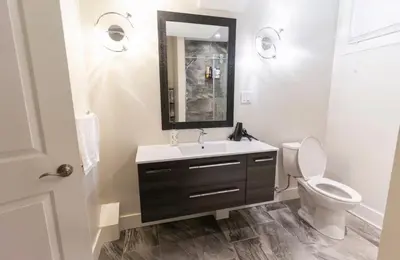 a bathroom with a sink and a toilet and a mirror at Modern Cozy Executive Suite with Private Entrance in London