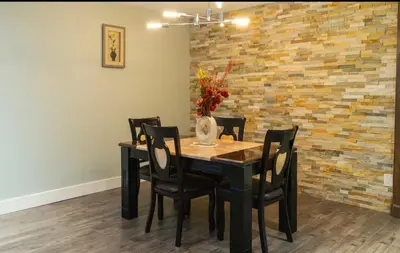 a dining room table with black chairs and a brick wall at Modern Cozy Executive Suite with Private Entrance in London