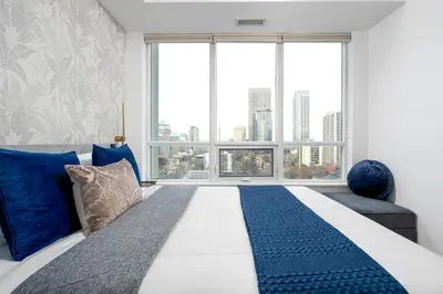 a bedroom with a bed and a large window at Comfort and Beauty in the heart of Tor | W Parking in Toronto