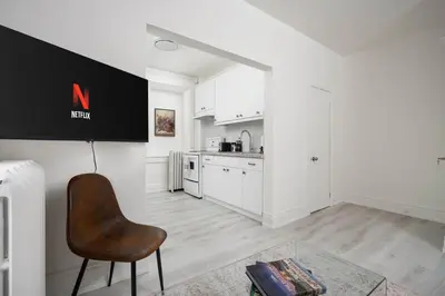 a kitchen with white cabinets and a chair in a room at Stylish Roncesvalles Flat in Toronto
