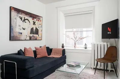 a living room with a black couch and a glass table at Stylish Roncesvalles Flat in Toronto