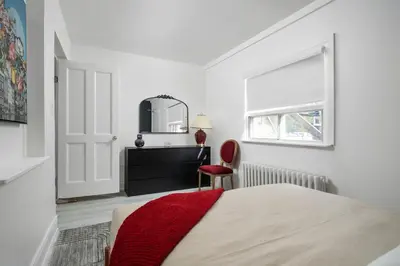a bedroom with a bed and a mirror and a chair at Stylish Roncesvalles Flat in Toronto