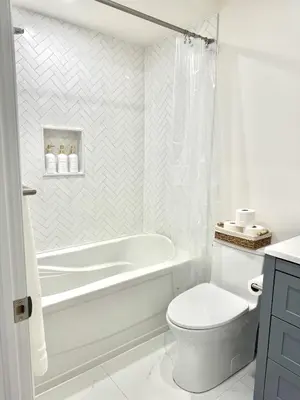 a white bathroom with a tub and a toilet at Bright & Cozy Private Studio Apartment in Toronto