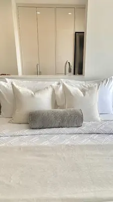 a white bed with white pillows and a mirror at Bright & Cozy Private Studio Apartment in Toronto