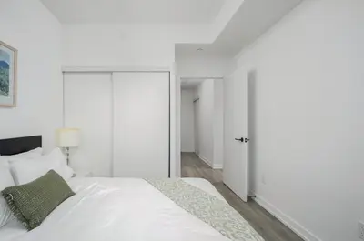 a bedroom with a white bed and a sliding door at Modern 2 Bed Condo in the Junction+Parking in Toronto