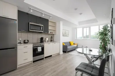 a kitchen and living room with a table and a couch at Modern 2 Bed Condo in the Junction+Parking in Toronto