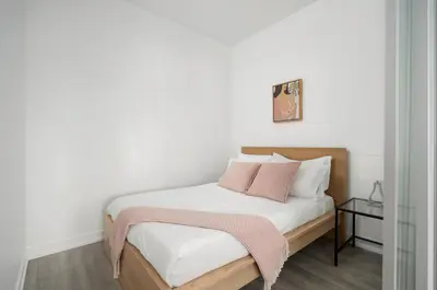 a bedroom with a bed with white sheets and pink pillows at Modern 2 Bed Condo in the Junction+Parking in Toronto