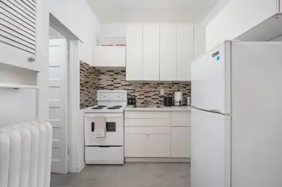 a kitchen with white cabinets and a white refrigerator at Vintage Charm on Roncesvalles in Toronto