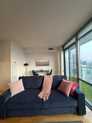 a blue couch with pillows in a room with windows at Brightly Lit Suite Centrally Located |UofT|Ryerson in Toronto