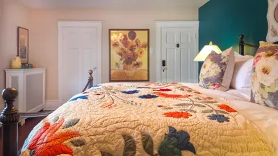 a bedroom with a bed with a colorful quilt on it at The Farmhouse Manor B&B in St. Catharines