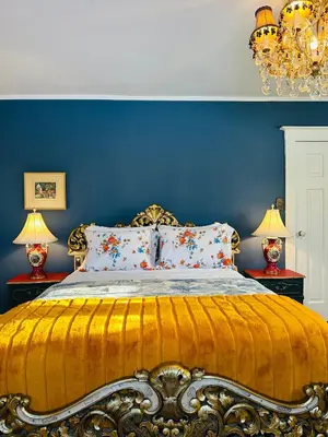 a bedroom with a bed with blue walls and two lamps at The Farmhouse Manor B&B in St. Catharines