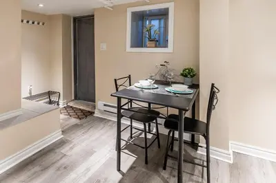 a kitchen and dining room with a black table and chairs at Cozy Suite Condo - Heart Of St Clair West - Bloor Hotel in Toronto
