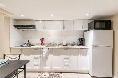 a kitchen with white cabinets and a white refrigerator at Cozy Suite Condo - Heart Of St Clair West - Bloor Hotel in Toronto