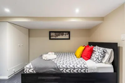 a room with a bed with colorful pillows on it at Cozy Suite Condo - Heart Of St Clair West - Bloor Hotel in Toronto