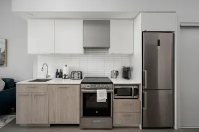 a kitchen with stainless steel appliances and white cabinets at Style & Comfort in the Heart of Toronto in Toronto